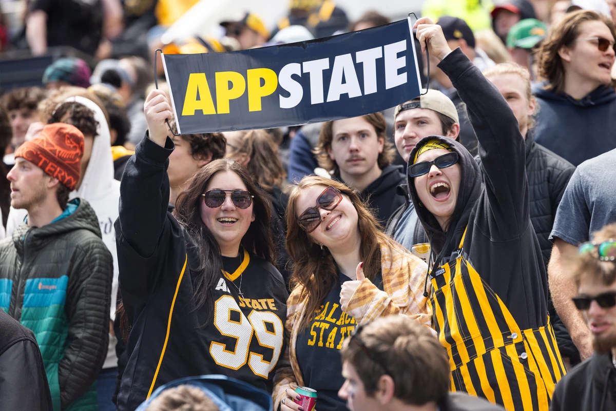 Students in a crowd holding up an App State sign at an athletic event.